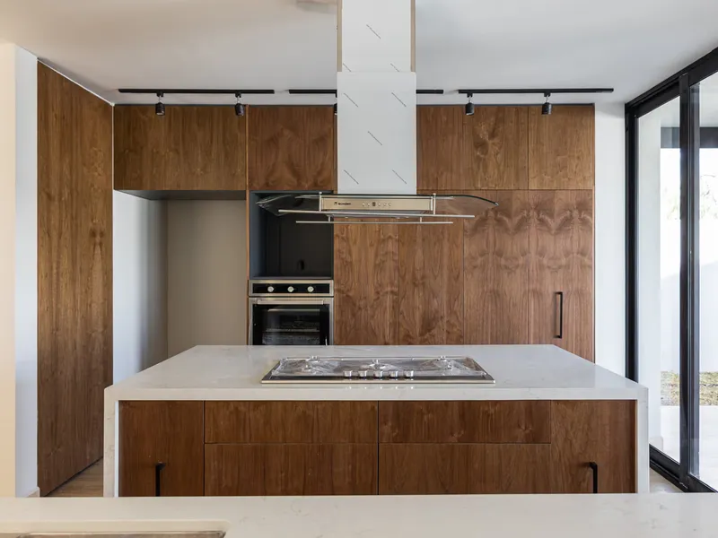 Cocina de Casa Roqueño 68 con gabinetes de nogal e isla con parrilla
